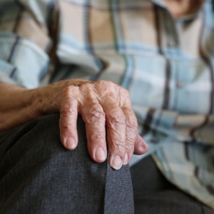 Close-up of elderly person's hand on their knee